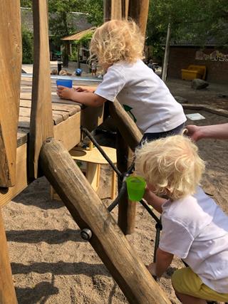 Børnene klatrer op på rutsjebane med kopper med vand i hånd